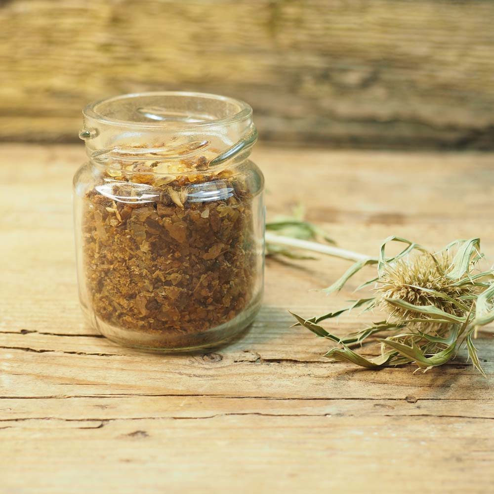 Nahaufnahme von granulierten Myrrhe-Stücken in einem Glasbehälter auf einem Holztisch